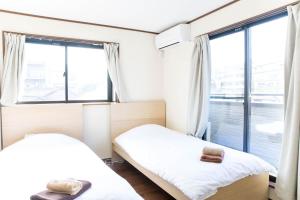 东京Tokyo Aoto House的带大窗户的客房内的两张床