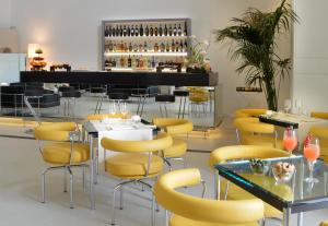 那不勒斯艾瑟达帕拉佐酒店的一间设有黄色桌椅的餐厅和一间酒吧