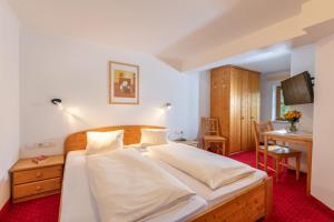 拉德施塔特纳斯内古特假日酒店的一间卧室配有一张带白色床单和一张桌子的床。