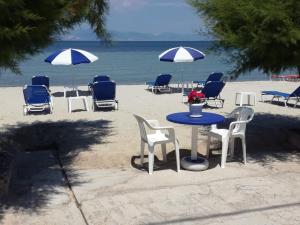 普里诺斯Rooms Ntontas的海滩上的桌椅和遮阳伞