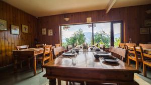 拉姆格尔Cedar Lodge By Aahma的一间带长桌和大窗户的用餐室