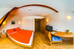 兰纳赫福鲁克斯佩森扎格勒霍夫酒店的一间卧室配有一张橙色的床和一张书桌
