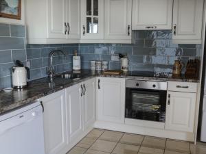 伦维尔Killary Bay View House的厨房配有白色橱柜和水槽
