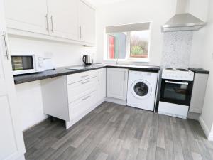 波弗特Ard Na Glen的厨房配有白色橱柜、洗衣机和烘干机