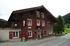 圣安特尼恩Berggasthaus Gemsli的街上的木房子,有红色百叶窗