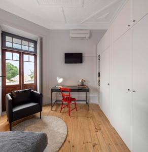 科英布拉Penedo da Saudade Suites & Hostel的客厅配有书桌和红色椅子