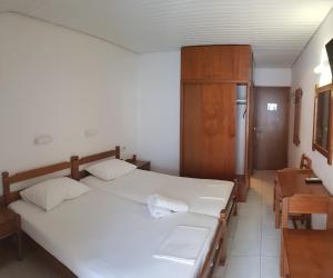 帕拉利亚卡泰里尼斯金星酒店的卧室配有2张白色的床和木制橱柜