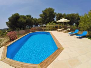 莱乌卡Villa Flora的一个带2把蓝色椅子和遮阳伞的游泳池