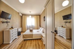 敖德萨Hotel Fusion的一间卧室配有一张床、两个梳妆台和电视。