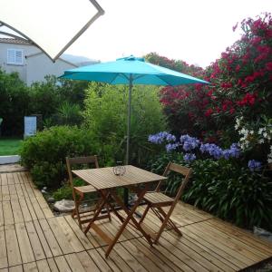 Borgo2 pièces indépendant avec son jardinet privé的一张木桌和两把椅子及雨伞