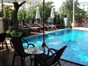 莱卡邦素万那普公寓酒店的游泳池旁带遮阳伞的桌子