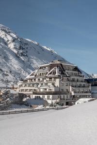 奥伯古格尔阿尔盆兰德酒店的山上的雪中一座白色的大建筑