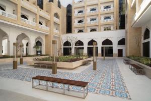 多哈Al Najada Doha Hotel Apartments by Oaks的庭院中间有长椅的建筑