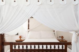 帕纳雷阿Quartara Boutique Hotel的卧室配有带白色窗帘的天蓬床