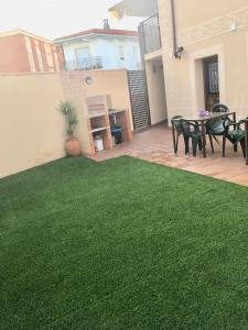 马尔帕尔蒂达德普拉森西亚Apartamentos Rurales el Trillo的后院拥有绿色的草地和桌椅