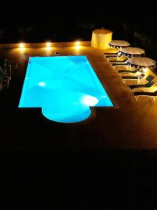 杰拉切Barone GR Macrì Agriturismo Modi的夜间游泳池,配有椅子和桌子