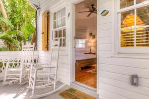 基韦斯特Key West Harbor Inn - Adults Only的前廊的白色房子,配有两把椅子