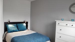 布里夫拉盖亚尔德Les Doctrinaires的一间卧室配有一张带蓝色枕头的床和梳妆台