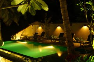 坦加拉Goyambokka Guesthouse的一个带桌椅的夜间游泳池