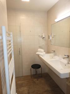 东蒂罗尔地区马特赖霍赫陶恩酒店的一间带水槽、镜子和凳子的浴室
