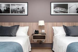 圣地亚哥Hotel Capital Bellet的酒店客房设有两张床和一张带台灯的桌子。