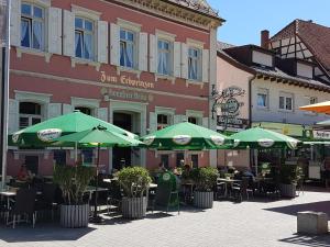 瓦尔多夫艾布帕林泽瓦尔多夫餐厅酒店的一组桌子,上面有绿色的雨伞,位于大楼前