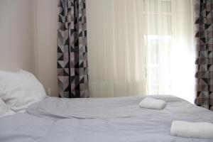 豪伊杜索博斯洛Aqua City Apartman的一张白色的床,窗户旁有两条毛巾