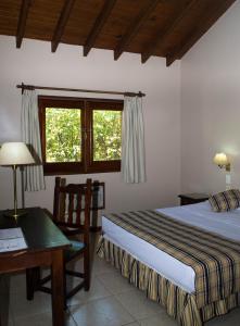 伊瓜苏港伊瓜苏马可波罗套房酒店的一间卧室配有一张床、一张书桌和一个窗户。