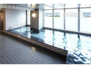 旭川旭川站前Y's酒店的一座大型游泳池,位于一座带窗户的建筑内