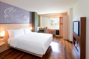 万象宜必思万象南富酒店的卧室配有白色的床和电视。