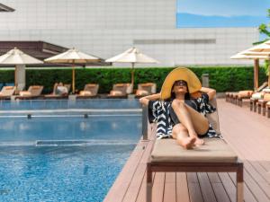 曼谷曼谷铂尔曼皇权酒店的坐在游泳池旁椅子上的戴帽子的女人