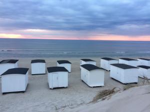 洛肯Luksus i Løkken的日落时在海滩上排排的海滩小屋