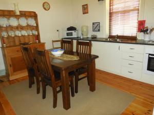 WaikerieAmalie Cottage Waikerie Unit 1的厨房配有木桌、椅子和水槽