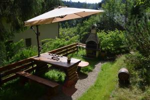 克雷尼察Luzik Krynica的花园里的野餐桌和遮阳伞