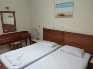 科斯镇雅尼斯开普敦公寓的一间卧室配有两张床、一张桌子和一面镜子