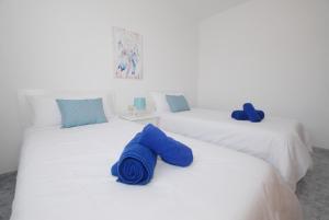 阿列塔Calma Suites La Garita的两张白色的床和蓝色毛巾