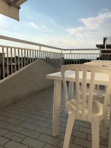 利多迪耶索罗Residence Moresco的阳台配有白色桌子和白色椅子