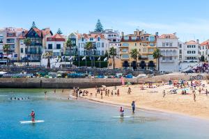 卡斯卡伊斯"Scandinavian" apartment in Cascais's old town的和冲浪板上的人一起在海滩上