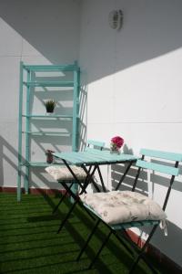 塞维利亚CLB Feria Apartment的一张桌子、两把椅子和一个玻璃架子
