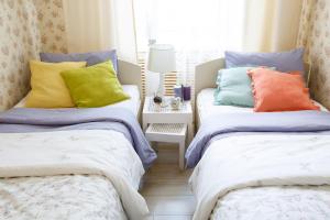 喀山Семейный Хостел "Дом 64"的卧室内的两张床和色彩缤纷的枕头