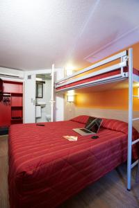 贝济耶普瑞米尔克拉斯贝兹尔酒店的一间卧室配有红色的床,上面有笔记本电脑