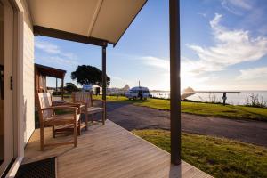 新普利茅斯环形路海滨假日公园酒店的一个带椅子的门廊,享有水景