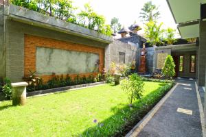 勒吉安Gempita House Bali的一座建筑旁的后院,拥有绿色草坪