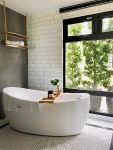鹅銮鼻美好生活旅店的带窗户的浴室内的白色大浴缸