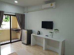 曼谷Prukpibul Apartment的客厅配有书桌、电视和桌子