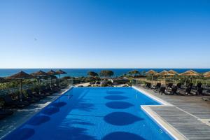 卡武埃鲁Vila Alba Resort的一个带椅子的游泳池,背景是大海