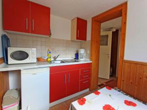 卢布明Ferienhaus Lubmin VORP 1451的一间带红色橱柜和微波炉的厨房