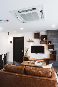 清迈Zivi Nimman的客厅配有棕色真皮沙发和平面电视。