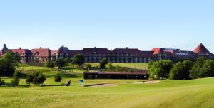 阿克菲尔德东萨西克斯国家酒店，高尔夫度假村&SPA的在一座大建筑前打高尔夫球的人