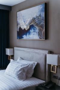 杜马格特PVL套房酒店的一张位于酒店客房的床铺,墙上挂着一幅画